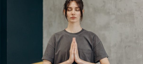 A woman meditating indoors with eyes closed, focusing on mindfulness and relaxation.